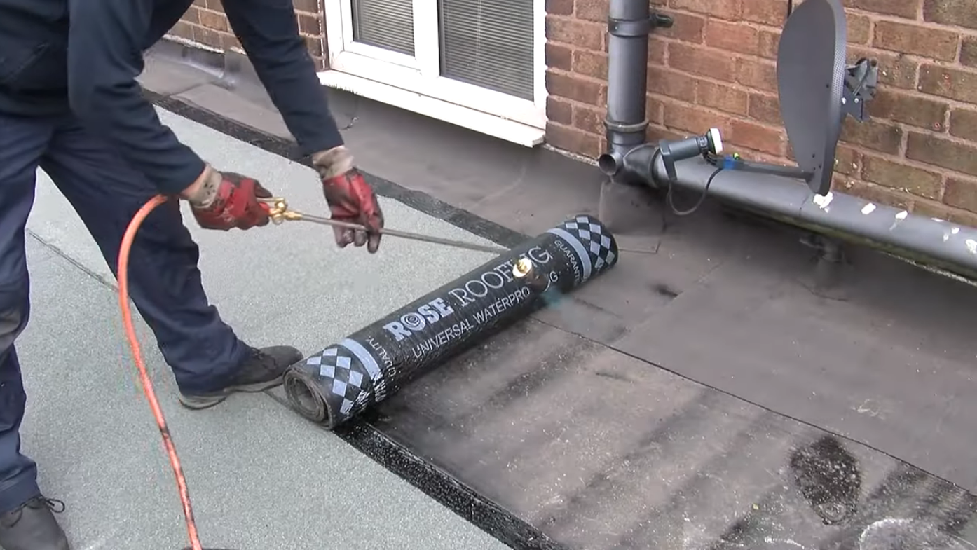 Roofer applying torch-on felt during a garage roof replacement in Stoke-on-Trent